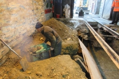 With excavation complete, the trench within the Engine Shed for the new drain is back-filled and compacted in layers ...