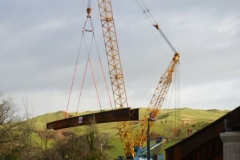 Southern Extension. New Dyfi Bridge scheme. Wednesday, 21.12.2022. A braced pair of main bridge beams take to the air under a huge crane ...