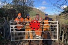21.11.2021. A visiting S&T gang from the Ffestiniog Railway attach some surplus red discs to Maes Y Llan gate…