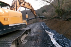 Later, the excavator picks up a fresh roll of geotextile and tracks it to the far end of the site ...